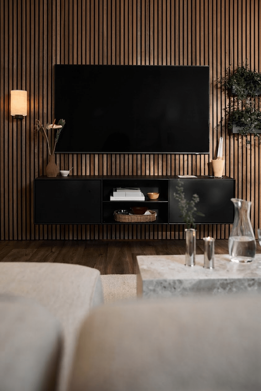 Nowoczesny salon z czarną szafką pod telewizor WoodUpp Arka, ścianą z listew Akupanel, minimalistycznymi akcentami oraz jasną sofą i stolikiem kawowym.